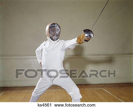 1960S Man Wear White Padded Protective Fencing Gear & Helmet Lunging At Camera Lunge En Garde Epee Sword View Large Photo Image Stock Image - 1960S Man Wear White Padded Protective Fencing Gear & Helmet Lunging At Camera Lunge En Garde Epee Sword. Fotosearch