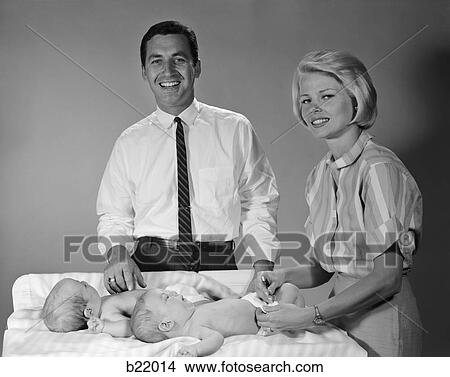 1960S Mother And Father With Twin Babies On Changing Table Smiling Indoor View Large Photo Image Picture - 1960S Mother And Father With Twin Babies On Changing Table Smiling Indoor . Fotosearch