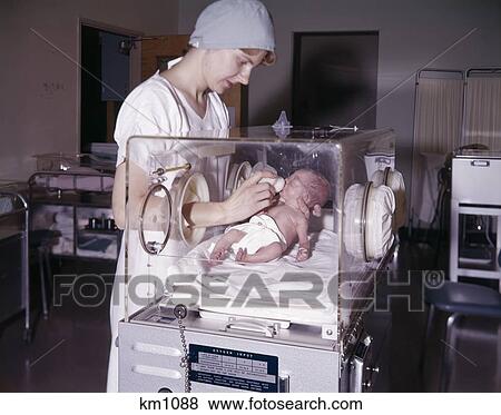 1960S Nurse Bottle Feeding Infant In Hospital Nursery Isolation Premature Intensive Care Woman View Large Photo Image Stock Photo - 1960S Nurse Bottle Feeding Infant In Hospital Nursery Isolation Premature Intensive Care Woman. Fotosearch