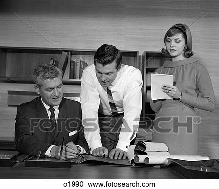 1960S Pair Of Businessmen Behind Desk Looking At Blueprints With Secretary At Side Taking Notes View Large Photo Image Stock Image - 1960S Pair Of Businessmen Behind Desk Looking At Blueprints With Secretary At Side Taking Notes . Fotosearch