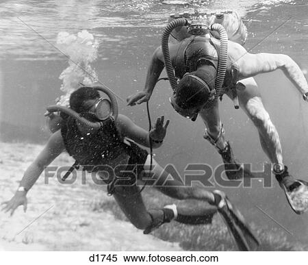 Stock Photography - 1960S Pair Of Divers With Tanks & Masks In Shallow Water Near Grassy Area Of Ocean Floor . Fotosearch