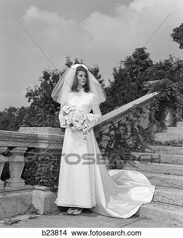 1960S Portrait Bride Holding Bouquet Of Daisies Standing On Ivy-Covered Stone Stairway Looking Off Into Distance View Large Photo Image Picture - 1960S Portrait Bride Holding Bouquet Of Daisies Standing On Ivy-Covered Stone Stairway Looking Off Into Distance . Fotosearch