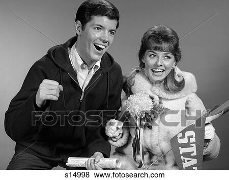 1960S Portrait Of Couple At Game Cheering She With Pennant & Corsage View Large Photo Image Stock Photo - 1960S Portrait Of Couple At Game Cheering She With Pennant & Corsage . Fotosearch