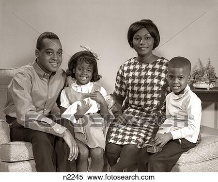 1960S Portrait Of Smiling Afro-American Family Seated In Living Room Daughter Holding Baby Doll View Large Photo Image Stock Photography - 1960S Portrait Of Smiling Afro-American Family Seated In Living Room Daughter Holding Baby Doll . Fotosearch