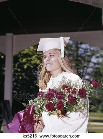 1960S Portrait Of Young Woman Graduate In White Cap And Gown Holding Bouquet Of Roses Outdoor View Large Photo Image Stock Photograph - 1960S Portrait Of Young Woman Graduate In White Cap And Gown Holding Bouquet Of Roses Outdoor . Fotosearch