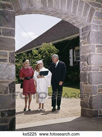 1960S Proud Parents With Graduate Daughter In Cap And Gown Under Archway Man Woman Girl High School College Three View Large Photo Image Stock Photography - 1960S Proud Parents With Graduate Daughter In Cap And Gown Under Archway Man Woman Girl High School College Three . Fotosearch