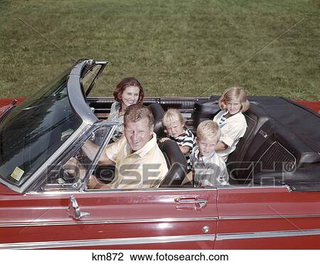 Stock Image - 1960S Retro Family Man Woman Boy Girl Father Mother Son Daughter Riding Together In Red Convertible Automobile. Fotosearch