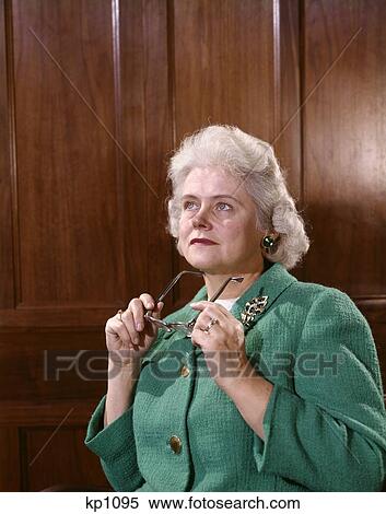 1960S Senior Elderly Woman Thoughtful Expression Serious Holding Glasses In Hand Look Up Wood Panel Background View Large Photo Image Stock Photography - 1960S Senior Elderly Woman Thoughtful Expression Serious Holding Glasses In Hand Look Up Wood Panel Background . Fotosearch