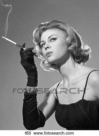 1960S Sexy Sultry Woman Black Dress Long Black Globes Bracelet Smoking Cigarette On Long Cigarette Holder Style Fashion View Large Photo Image Stock Photography - 1960S Sexy Sultry Woman Black Dress Long Black Globes Bracelet Smoking Cigarette On Long Cigarette Holder Style Fashion . Fotosearch