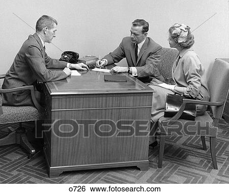 1960S Side View Of Couple Sitting At Desk With Executive Signing Papers View Large Photo Image Stock Photograph - 1960S Side View Of Couple Sitting At Desk With Executive Signing Papers . Fotosearch