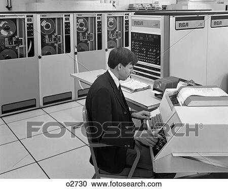 Stock Image - 1960S Side View Of Man In Jacket & Tie Operating Large Computer Terminal . Fotosearch