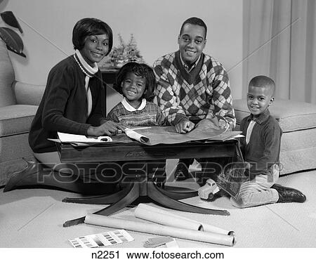 1960S Smiling Afro-American Family Seated Behind Coffee Table Looking At Blueprints View Large Photo Image Stock Image - 1960S Smiling Afro-American Family Seated Behind Coffee Table Looking At Blueprints . Fotosearch