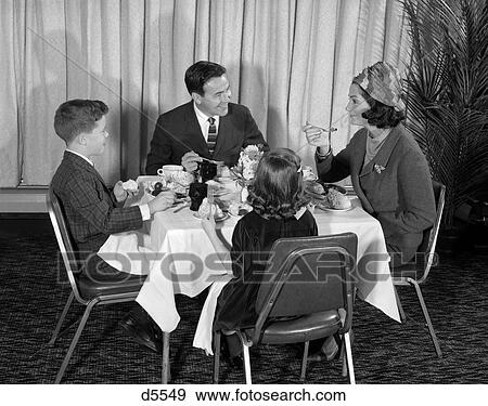 1960S Smiling Happy Family Of 4 Eating Meal In Restaurant Mom Wear Turban Style Hat Dad Talking To Mother Son Daughter Boy Girl View Large Photo Image Stock Photo - 1960S Smiling Happy Family Of 4 Eating Meal In Restaurant Mom Wear Turban Style Hat Dad Talking To Mother Son Daughter Boy Girl. Fotosearch
