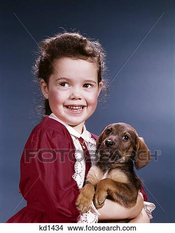 Picture - 1960S Smiling Little Girl Red Dress Holding Puppy Dog Pet. Fotosearch