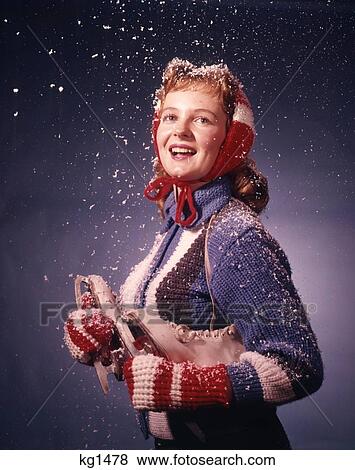 1960S Smiling Woman Wearing Red Mittens Ear Muffs And Blue Sweater Holding Ice Skates In Falling Winter Snow Studio View Large Photo Image Stock Photo - 1960S Smiling Woman Wearing Red Mittens Ear Muffs And Blue Sweater Holding Ice Skates In Falling Winter Snow Studio . Fotosearch