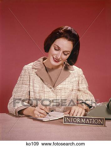 Stock Photo - 1960S Smiling Woman Writing In Note Book Beside Telephone At Information Desk Studio . Fotosearch