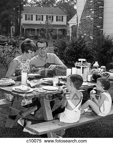 Stock Photography - 1960S Suburban Family Of Four At Picnic Table In Backyard Eating . Fotosearch