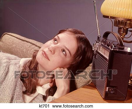 1960S Teenage Girl In Living Room Chair Listening To Portable Radio With Daydream Pensive Expression View Large Photo Image Stock Image - 1960S Teenage Girl In Living Room Chair Listening To Portable Radio With Daydream Pensive Expression . Fotosearch