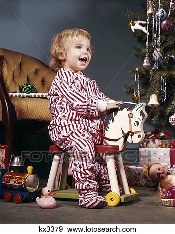 1960S Toddler Girl On Wheeled Toy Riding Horse Near Christmas Tree Living Room Happy Smiling View Large Photo Image Stock Photo - 1960S Toddler Girl On Wheeled Toy Riding Horse Near Christmas Tree Living Room Happy Smiling. Fotosearch