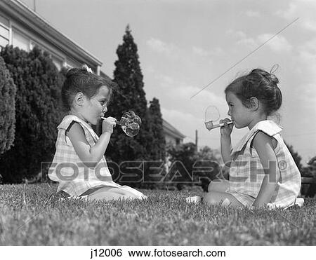 1960S Twin Girls Sitting Grass Blowing Bubbles Outdoor Summer Fun View Large Photo Image Stock Photograph - 1960S Twin Girls Sitting Grass Blowing Bubbles Outdoor Summer Fun . Fotosearch