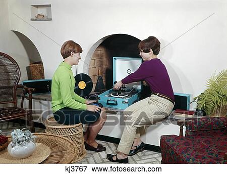 1960S Two Teenaged Girls Playing Records On Player In Wall Niche In Living Room View Large Photo Image Stock Photo - 1960S Two Teenaged Girls Playing Records On Player In Wall Niche In Living Room . Fotosearch