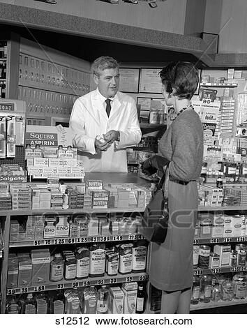 1960S Woman Counter Pharmacy Talk Talking Pharmacist Buying Drugs Product Customer Sales Service Retro Drug Store View Large Photo Image Stock Image - 1960S Woman Counter Pharmacy Talk Talking Pharmacist Buying Drugs Product Customer Sales Service Retro Drug Store . Fotosearch