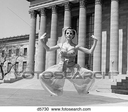 1960S Woman In Middle Eastern Belly Dance Costume Jumping Legs In Plie In Front Of Building With Greek Style Columns Outdoor View Large Photo Image Stock Image - 1960S Woman In Middle Eastern Belly Dance Costume Jumping Legs In Plie In Front Of Building With Greek Style Columns Outdoor. Fotosearch