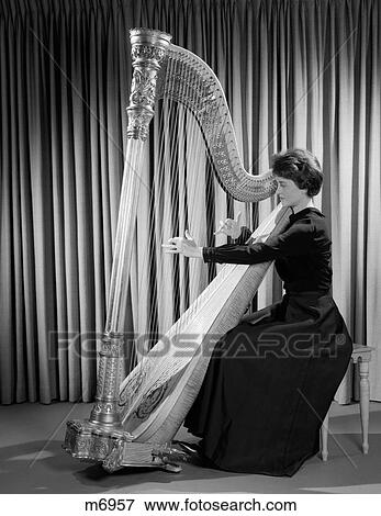 Stock Photo - 1960S Woman Musician In Formal Dress Performing Playing Harp On Stage . Fotosearch