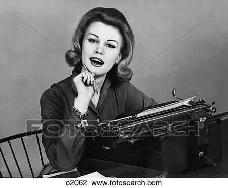 Stock Image - 1960S Woman Secretary Smiling At Camera Seated At Desk Typewriter Charm Bracelet On Wrist . Fotosearch