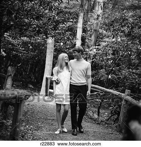 1960S Young Couple Man Woman Blonde Walking Outside Path Bridge Romance Date Flirt Nature Forest Park Woods View Large Photo Image Stock Image - 1960S Young Couple Man Woman Blonde Walking Outside Path Bridge Romance Date Flirt Nature Forest Park Woods . Fotosearch