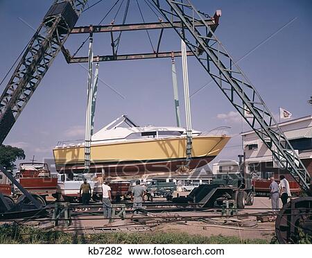 Stock Image - Boat Speed Boat Being Lifted On Cranes Men Working. Fotosearch