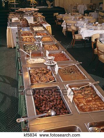 Picture - Buffet Of Hot Foods In Banquet Room Dessert Table In Background. Fotosearch