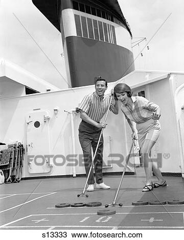 Stock Image - Couple Man Woman Shipboard Play Playing Shuffle Board Aboard Ship Expression Fun Happy Vacation Summer 1960S Retro . Fotosearch