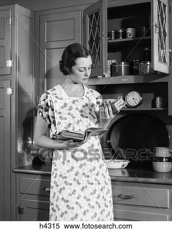1920s 1930s woman housewife wearing apron in kitchen holding cookbook reading package of corn starch View Large Photo Image Stock Photography - 1920s 1930s woman housewife wearing apron in kitchen holding cookbook reading package of corn starch. Fotosearch