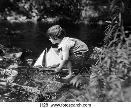 1920s child sailing sailboat stream View Large Photo Image Stock Photo - 1920s child sailing sailboat stream. Fotosearch