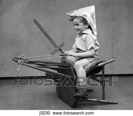 1930s boy playing wooden sword paper hat riding chair like a horse View Large Photo Image Stock Image - 1930s boy playing wooden sword paper hat riding chair like a horse. Fotosearch