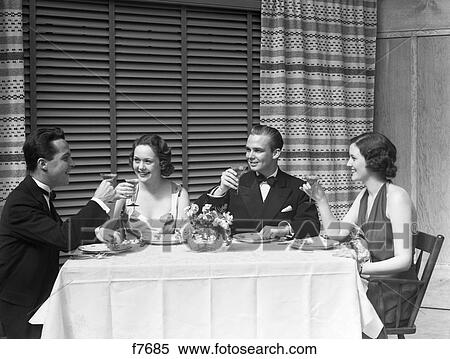 Stock Photography - 1930s dinner party two couples in formal evening dress toasting. Fotosearch