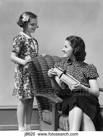 Stock Image - 1930s girl with woman female chair gift present smiling. Fotosearch