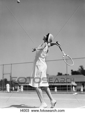 1930s woman playing tennis about to hit ball with racket View Large Photo Image Stock Image - 1930s woman playing tennis about to hit ball with racket. Fotosearch