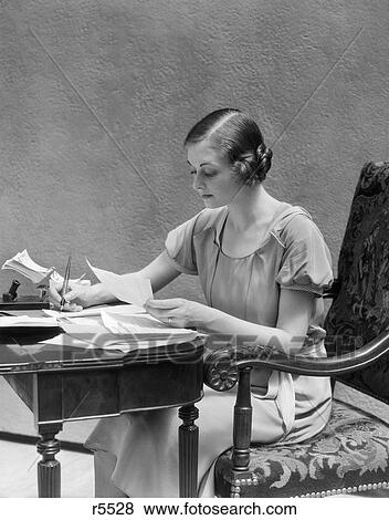 1930s woman sitting at desk doing paperwork paying bills writing with fountain pen View Large Photo Image Stock Photo - 1930s woman sitting at desk doing paperwork paying bills writing with fountain pen. Fotosearch