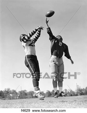 1940s 1950s two men playing football both reaching for ball in mid air View Large Photo Image Stock Photo - 1940s 1950s two men playing football both reaching for ball in mid air. Fotosearch
