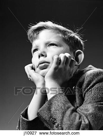 Stock Photo - 1940s bored serious boy waiting chin resting in hands. Fotosearch