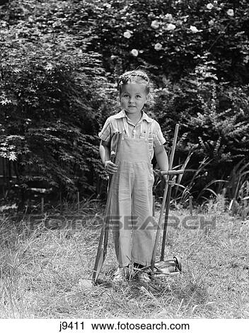 1940s child holding lawn tools work clothes grass View Large Photo Image Stock Image - 1940s child holding lawn tools work clothes grass. Fotosearch