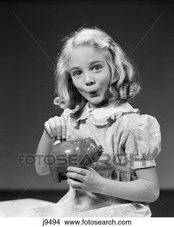 1940s child putting money coin into piggy bank View Large Photo Image Picture - 1940s child putting money coin into piggy bank. Fotosearch