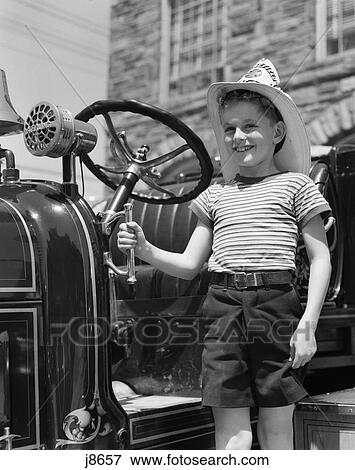 1940s child standing next to fire engine hat smiling View Large Photo Image Stock Photo - 1940s child standing next to fire engine hat smiling. Fotosearch