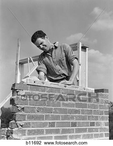 1940s man working with level on brick wall chimney construction View Large Photo Image Stock Image - 1940s man working with level on brick wall chimney construction. Fotosearch