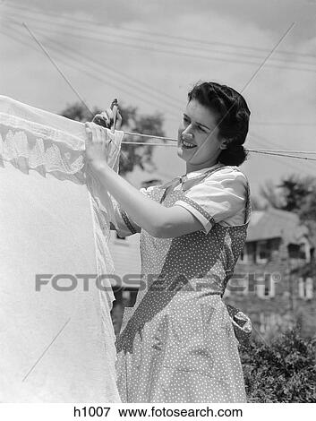 Stock Photo - 1940s woman hanging laundry on clothesline outdoors. Fotosearch