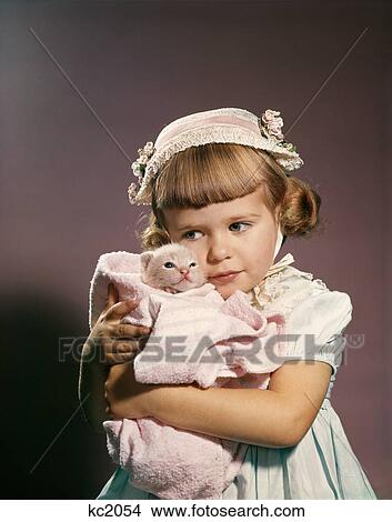 1950s 1960s little girl in easter hat hugging a kitten studio View Large Photo Image Picture - 1950s 1960s little girl in easter hat hugging a kitten studio. Fotosearch