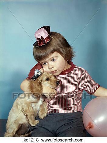 1950s 1960s little girl wearing party hat frowning hugging a cocker spaniel puppy with balloons studio View Large Photo Image Stock Photo - 1950s 1960s little girl wearing party hat frowning hugging a cocker spaniel puppy with balloons studio. Fotosearch