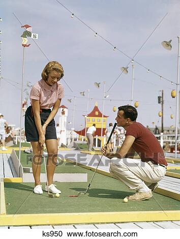 1950s 1960s young couple man woman playing summer amusement miniature golf game View Large Photo Image Stock Image - 1950s 1960s young couple man woman playing summer amusement miniature golf game. Fotosearch